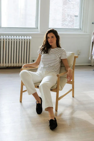 Woman sitting on a chair in a room with large windows and a radiator.