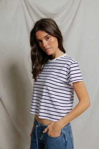 Woman wearing a striped shirt and jeans against a plain background