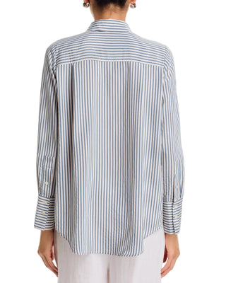 A woman shown from the back wearing a long-sleeve button-up shirt with vertical navy and white stripes, paired with light-colored pants against a plain white background.