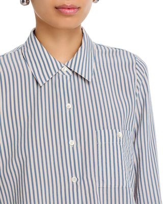Close-up of a person wearing a collared button-front shirt with narrow vertical blue and off-white stripes, plus a chest pocket and white buttons.