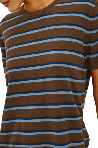 A close-up of a person wearing a brown short-sleeve crewneck t-shirt with horizontal stripes in navy blue and light blue.