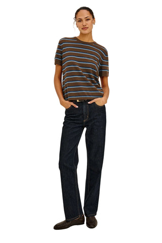 Person wearing a striped shirt and dark jeans on a plain background