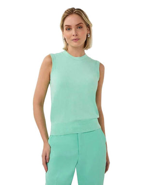 Woman wearing a mint green sleeveless top and pants against a light gray background