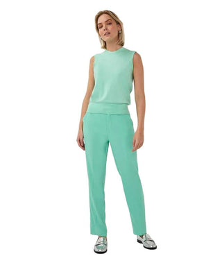 Woman wearing a mint green sleeveless top and pants on a white background