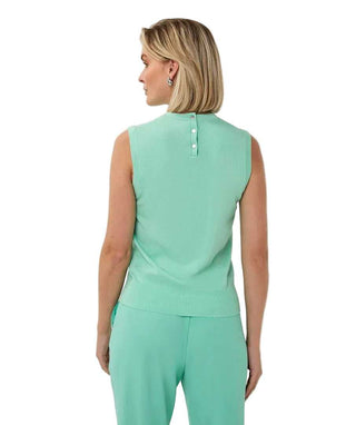 Woman wearing a green sleeveless top and pants on a white background